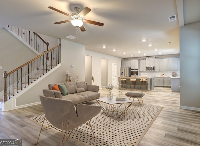 living room with light hardwood / wood-style floors and ceiling fan