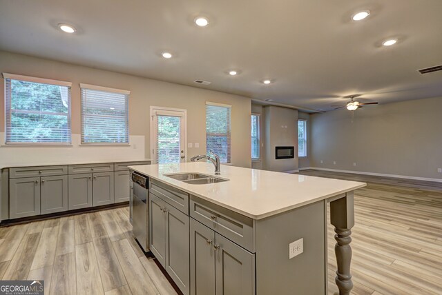 kitchen featuring light hardwood / wood-style floors, sink, gray cabinetry, a center island with sink, and ceiling fan