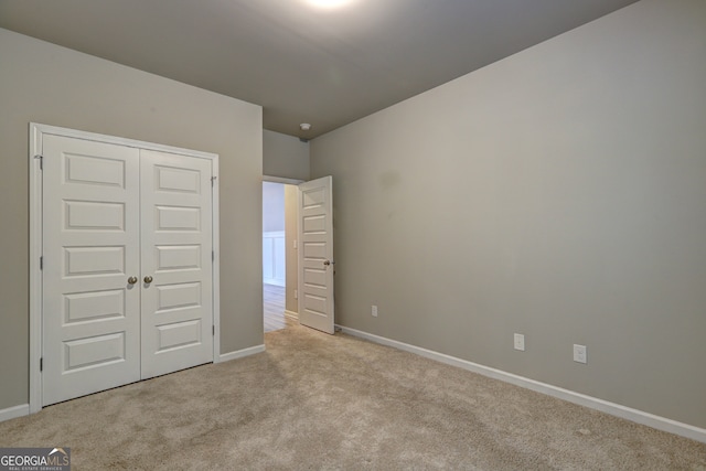 unfurnished bedroom featuring light carpet and a closet