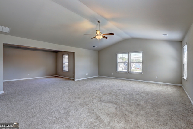 carpeted spare room featuring a wealth of natural light, lofted ceiling, and ceiling fan