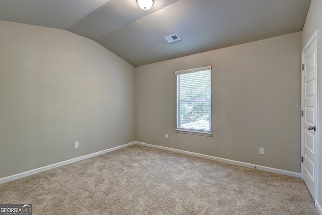 carpeted spare room featuring vaulted ceiling