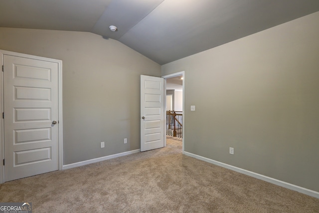 unfurnished bedroom featuring light colored carpet and lofted ceiling