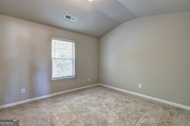 spare room with light carpet and vaulted ceiling