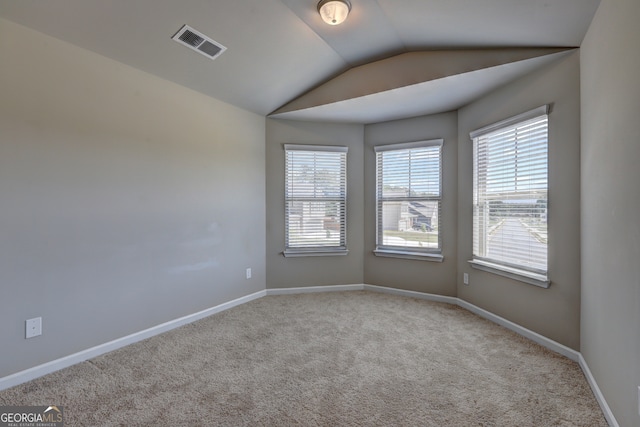 empty room featuring light colored carpet and vaulted ceiling