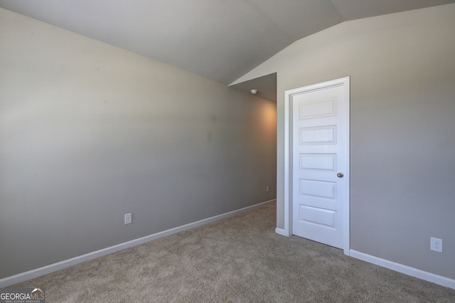 empty room featuring vaulted ceiling and light carpet