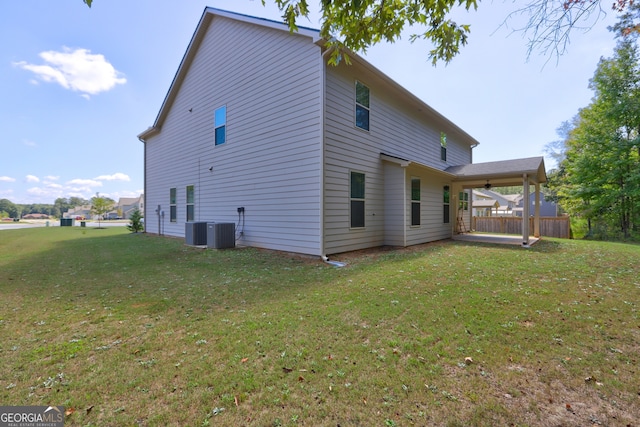 rear view of house with central AC unit and a lawn