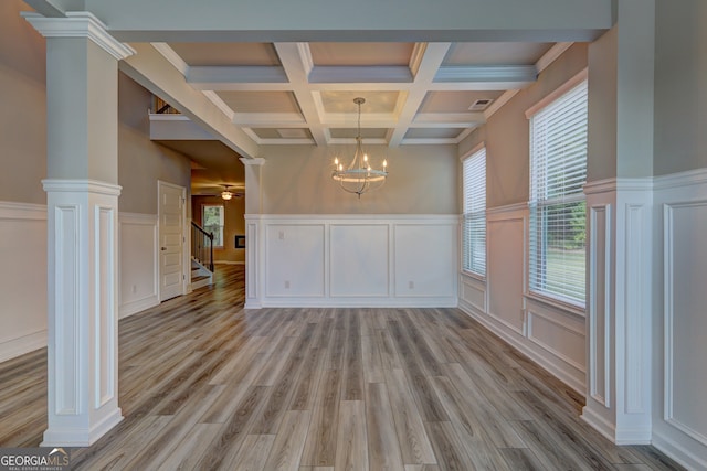 spare room with coffered ceiling, ornate columns, beam ceiling, light hardwood / wood-style flooring, and a chandelier