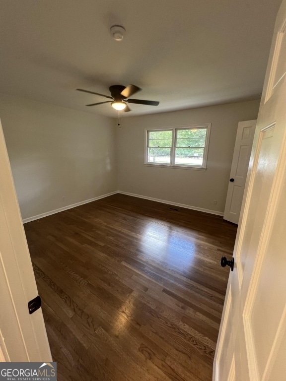 empty room featuring ceiling fan, dark hardwood / wood-style floors, and a healthy amount of sunlight