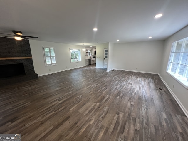 unfurnished living room featuring dark wood-type flooring, ceiling fan, and a fireplace