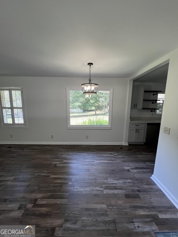 unfurnished dining area featuring a notable chandelier and dark hardwood / wood-style flooring