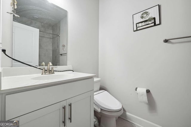 bathroom featuring tiled shower, vanity, and toilet