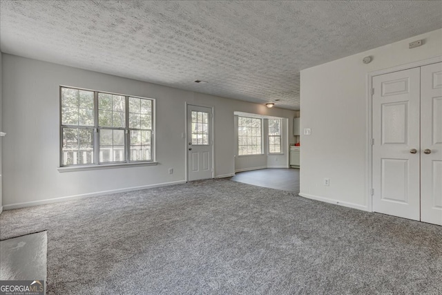 unfurnished living room featuring dark carpet and a textured ceiling