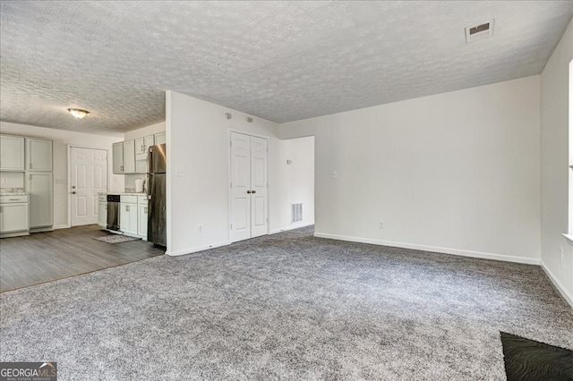 unfurnished living room with a textured ceiling and carpet flooring