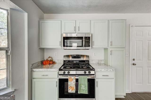 kitchen featuring light stone countertops, stainless steel appliances, a textured ceiling, and dark hardwood / wood-style floors