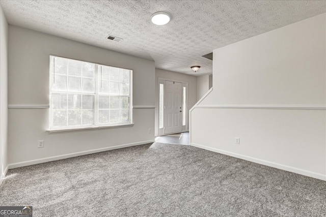 unfurnished living room featuring a textured ceiling and carpet