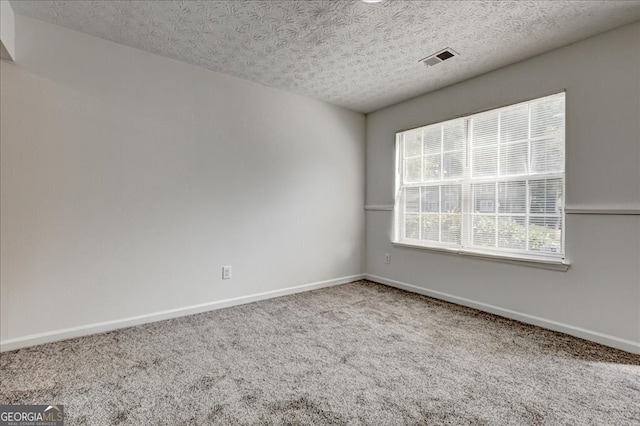 unfurnished room featuring carpet and a textured ceiling