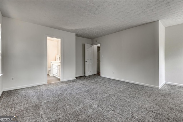 unfurnished bedroom with a textured ceiling, ensuite bath, and carpet flooring