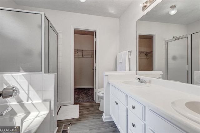 bathroom with vanity, a textured ceiling, hardwood / wood-style flooring, toilet, and an enclosed shower