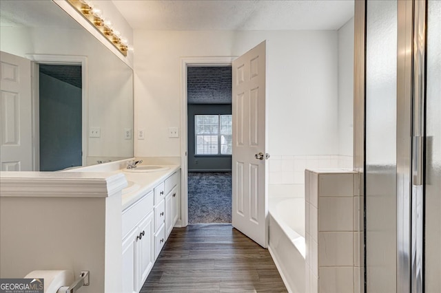 bathroom with a textured ceiling, wood-type flooring, vanity, and a washtub