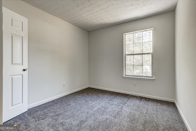 spare room with a textured ceiling and carpet