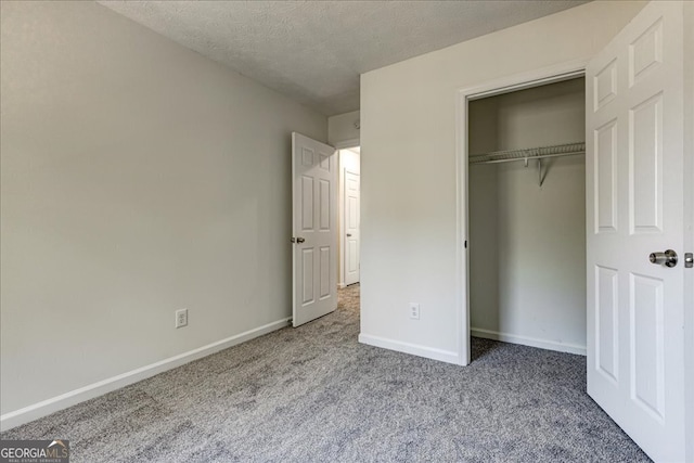 unfurnished bedroom featuring light carpet, a textured ceiling, and a closet