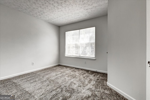 carpeted empty room featuring a textured ceiling