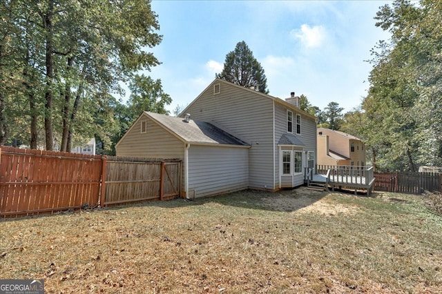 rear view of house with a wooden deck and a lawn