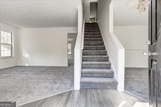 stairway featuring a textured ceiling, ornamental molding, and carpet floors