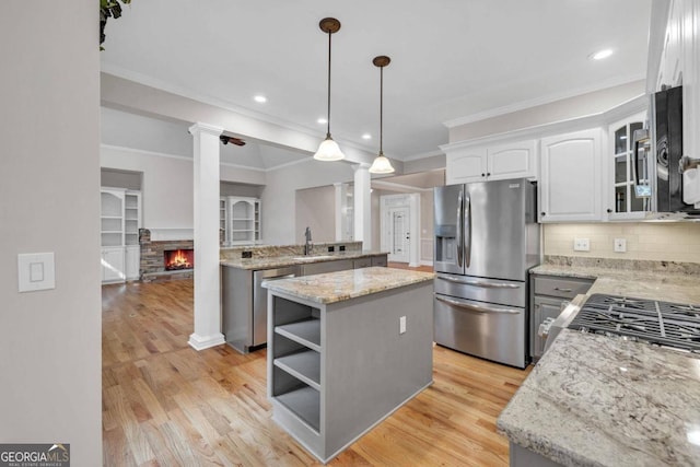 kitchen with white cabinets, stainless steel appliances, decorative columns, a center island, and light wood-type flooring