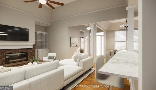 living room featuring hardwood / wood-style flooring, ceiling fan with notable chandelier, and a brick fireplace