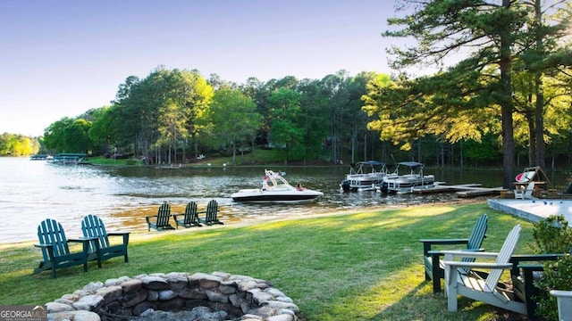 exterior space with a lawn, a dock, a water view, and an outdoor fire pit