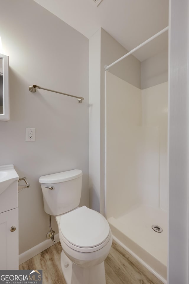 bathroom featuring vanity, hardwood / wood-style flooring, toilet, and a shower