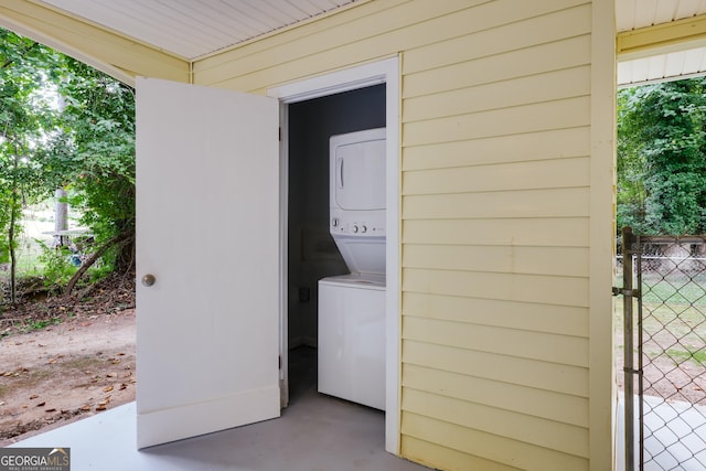 laundry area featuring stacked washer and clothes dryer and wood walls