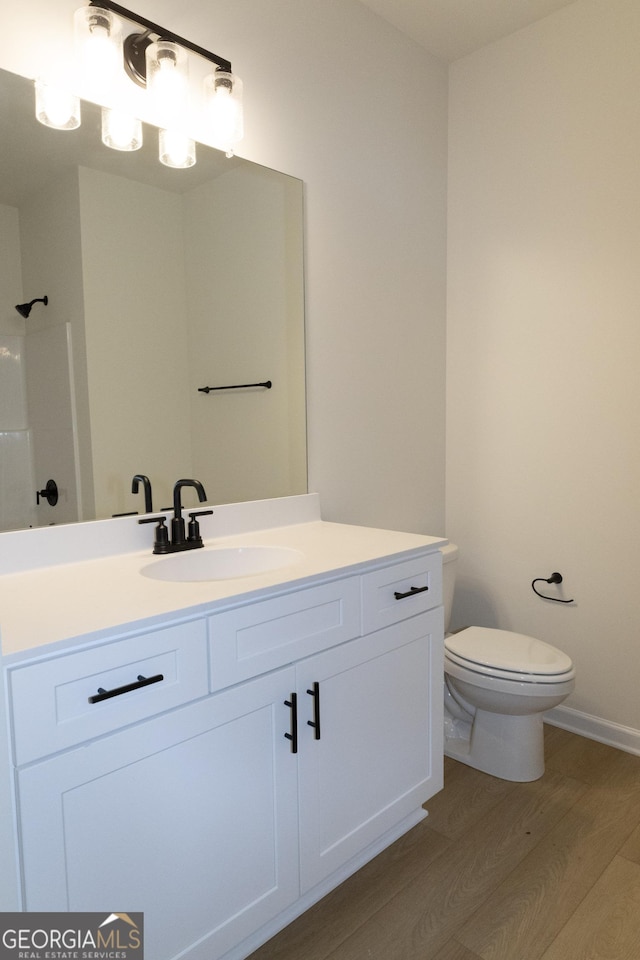 bathroom featuring vanity, toilet, wood-type flooring, and walk in shower