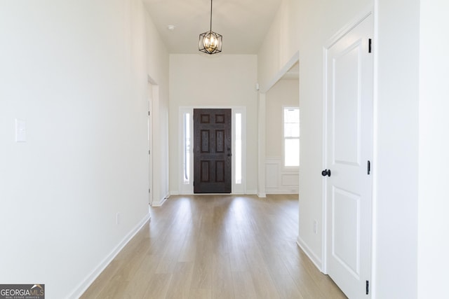 entryway featuring a towering ceiling, a chandelier, and light wood-type flooring