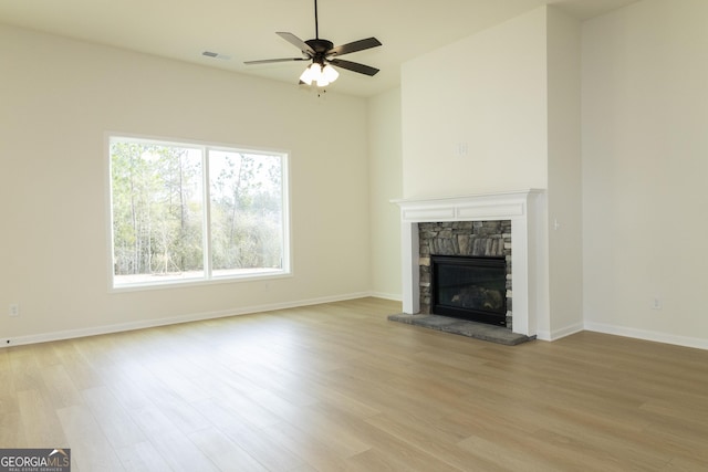 unfurnished living room with a fireplace, light wood-type flooring, and ceiling fan