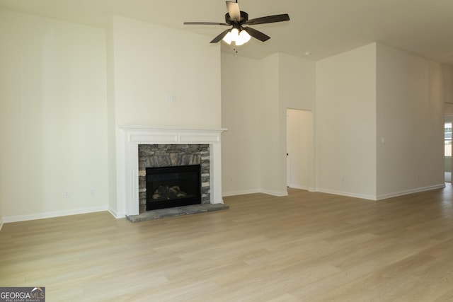 unfurnished living room with ceiling fan, light wood-type flooring, and a fireplace