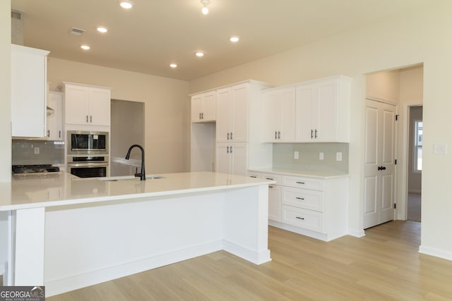 kitchen featuring appliances with stainless steel finishes, light hardwood / wood-style floors, white cabinetry, and sink