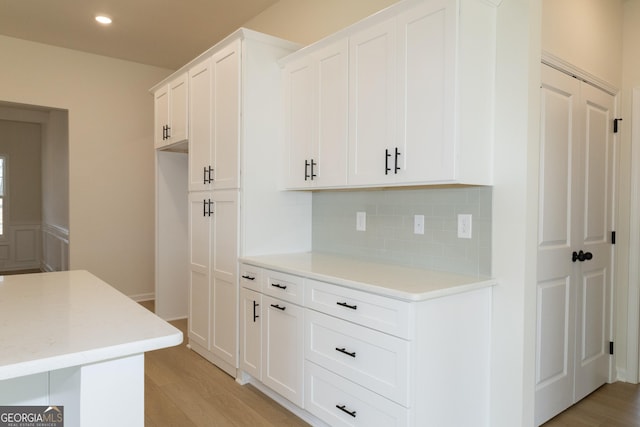 kitchen featuring decorative backsplash, white cabinetry, and light hardwood / wood-style flooring