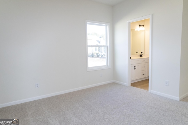 unfurnished bedroom with light colored carpet, sink, and connected bathroom