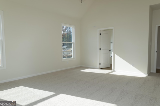 spare room with light carpet and high vaulted ceiling