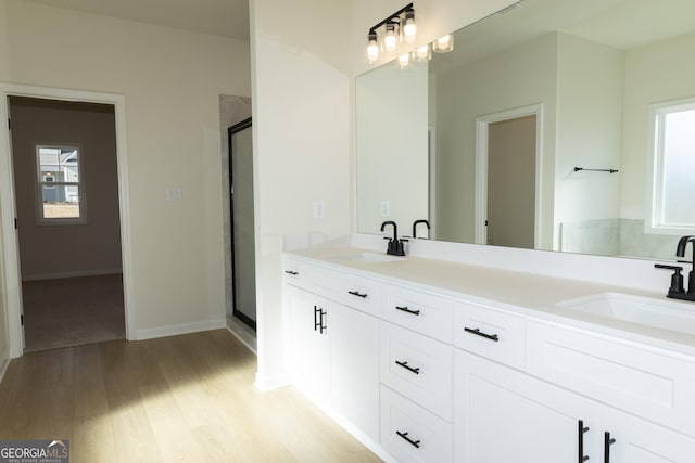 bathroom with hardwood / wood-style floors, vanity, and a shower with door