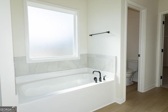 bathroom featuring hardwood / wood-style floors, a bath, and toilet