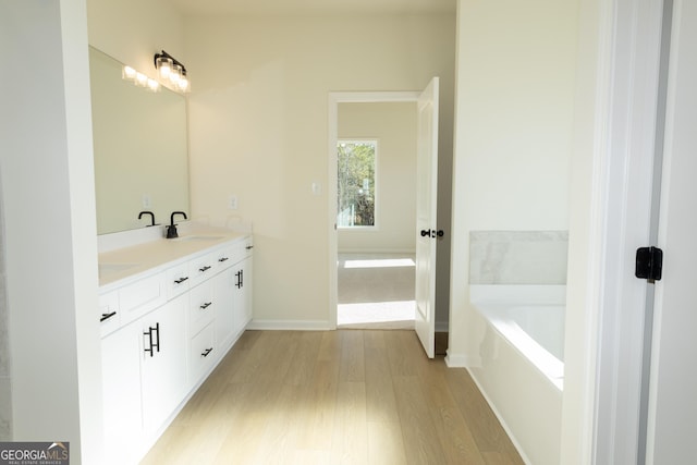 bathroom with a washtub, hardwood / wood-style floors, and vanity