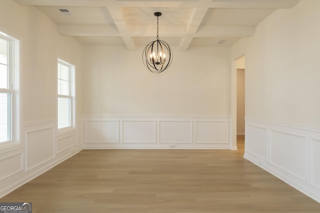 unfurnished dining area featuring beamed ceiling, light hardwood / wood-style flooring, coffered ceiling, and a notable chandelier