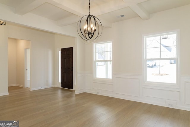 unfurnished dining area featuring a notable chandelier, plenty of natural light, wood-type flooring, and beamed ceiling