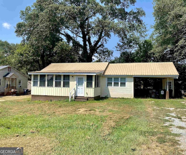 single story home with a carport, entry steps, a front lawn, and metal roof