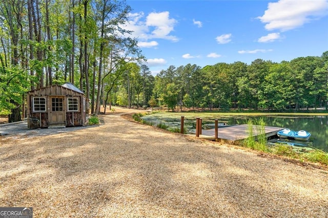 view of yard featuring an outdoor structure, a dock, and a water view