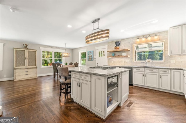 kitchen featuring backsplash, a kitchen island, white cabinetry, dark wood-type flooring, and pendant lighting