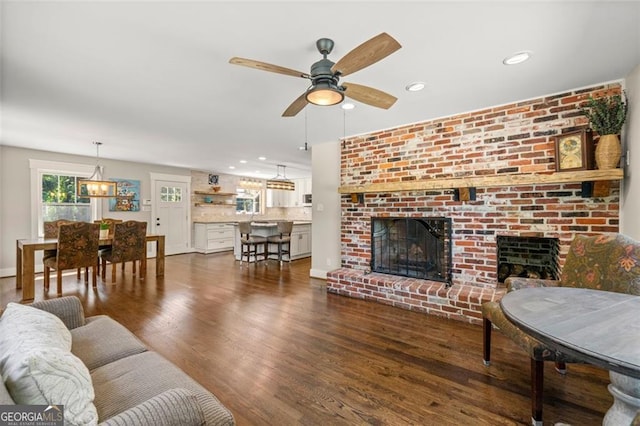 living room featuring ceiling fan, a fireplace, and dark hardwood / wood-style flooring